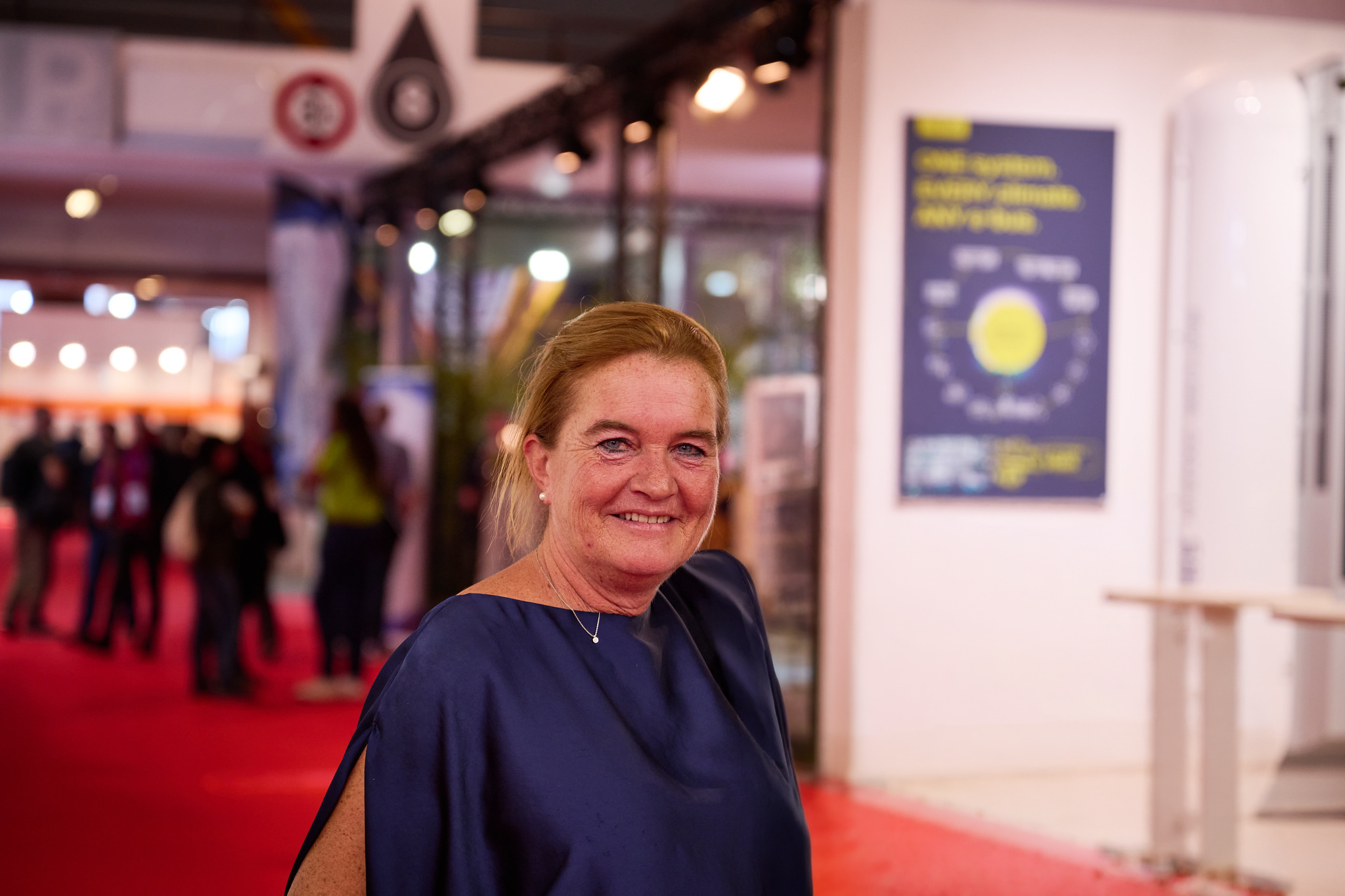 Mieke from Busworld at Busworld Europe 2025 in Brussels, Belgium, with the international bus and coach exhibition in the background.
